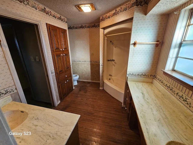 full bathroom featuring hardwood / wood-style flooring, vanity, toilet, and a textured ceiling