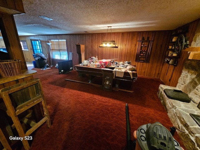 carpeted dining space with a fireplace, a textured ceiling, and wood walls