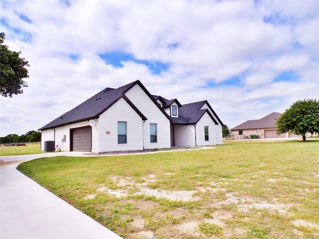 view of front of home with a garage, central AC, and a front yard