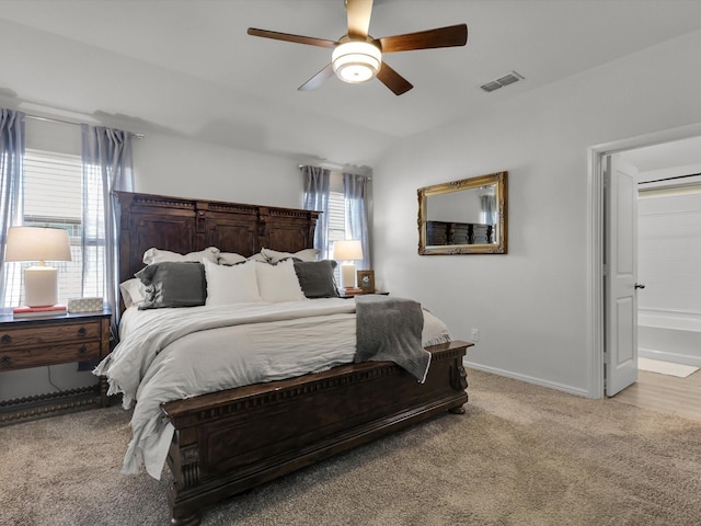 bedroom with lofted ceiling, ensuite bath, light colored carpet, and ceiling fan