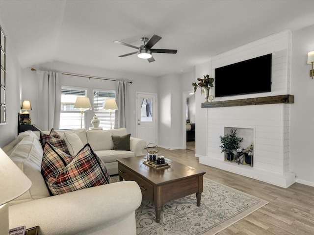 living room with a large fireplace, ceiling fan, and light hardwood / wood-style flooring