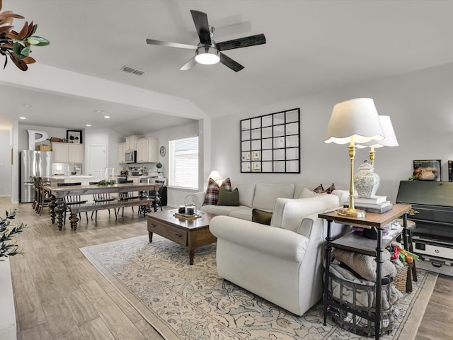 living room with vaulted ceiling, ceiling fan, and light hardwood / wood-style flooring