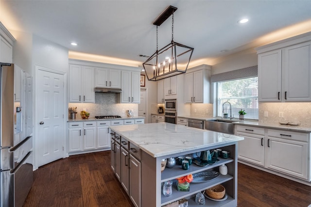 kitchen with sink, appliances with stainless steel finishes, white cabinetry, dark hardwood / wood-style floors, and a kitchen island