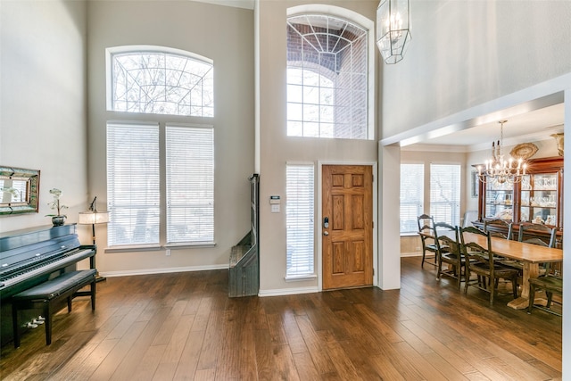 entrance foyer with ornamental molding, dark hardwood / wood-style flooring, a high ceiling, and a notable chandelier