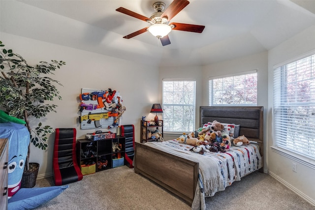 carpeted bedroom with ceiling fan and a tray ceiling