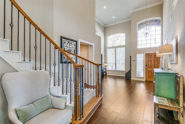 foyer featuring a towering ceiling, ornamental molding, dark hardwood / wood-style flooring, and a notable chandelier