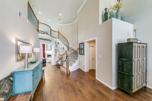 foyer entrance featuring crown molding, dark hardwood / wood-style flooring, and a high ceiling