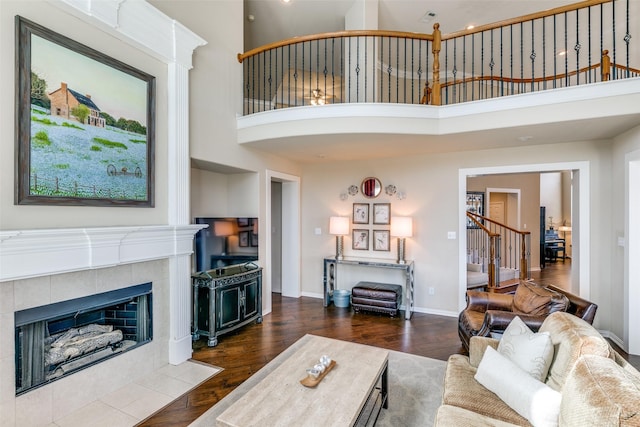 living room featuring dark hardwood / wood-style floors, a towering ceiling, and a fireplace