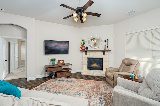 living room with ceiling fan and a stone fireplace