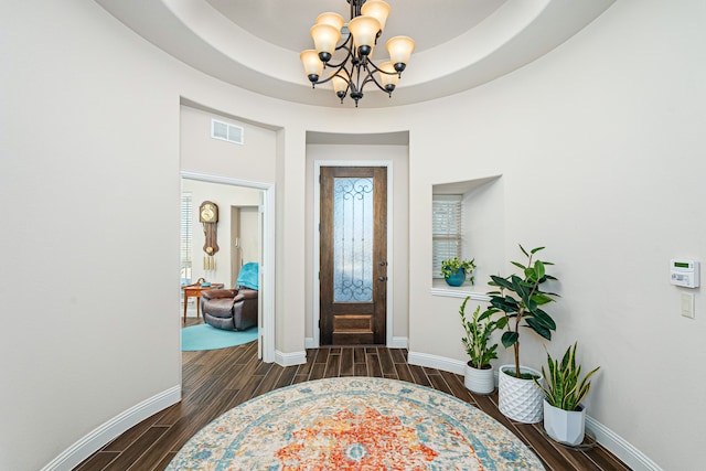 entrance foyer with a raised ceiling and a notable chandelier