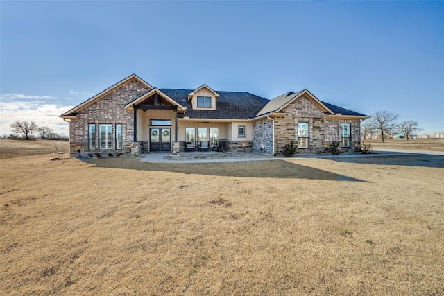 craftsman-style home with a front lawn and french doors