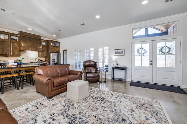 living room featuring french doors, crown molding, and sink