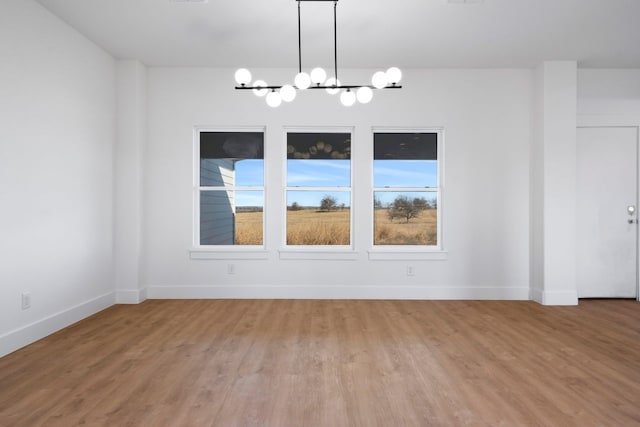 unfurnished dining area with hardwood / wood-style flooring and a chandelier