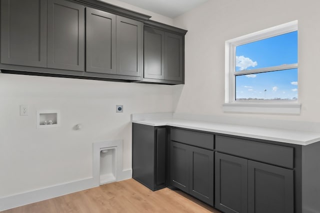 laundry room with gas dryer hookup, cabinets, hookup for a washing machine, hookup for an electric dryer, and light hardwood / wood-style floors