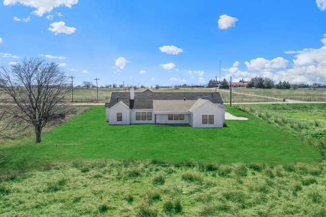 rear view of property with a rural view and a lawn