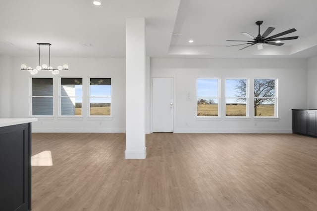 unfurnished living room featuring a raised ceiling, plenty of natural light, and light hardwood / wood-style flooring