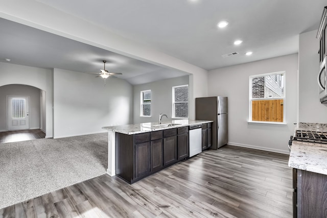 kitchen with light stone counters, stainless steel appliances, sink, and dark brown cabinets