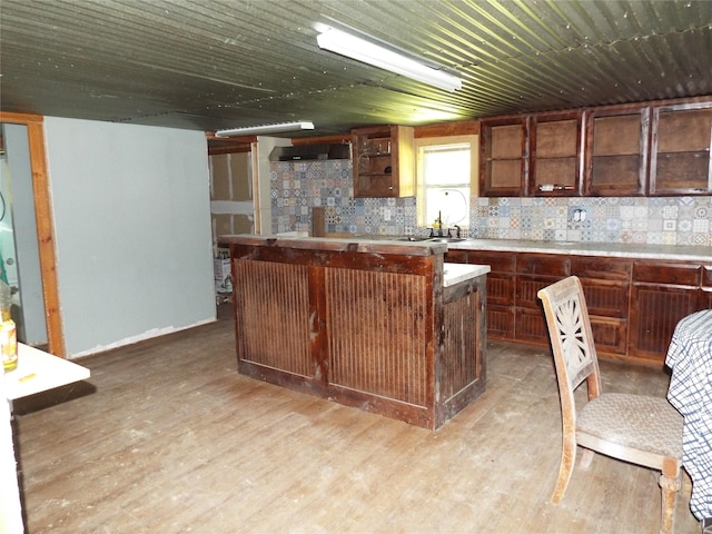 kitchen with dark brown cabinetry, a kitchen island, and light hardwood / wood-style flooring