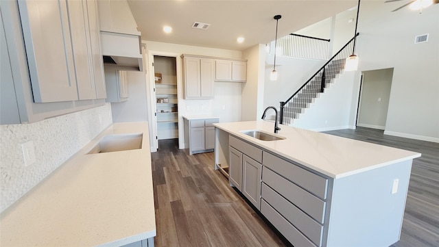 kitchen featuring gray cabinets, dark hardwood / wood-style floors, pendant lighting, sink, and a center island with sink