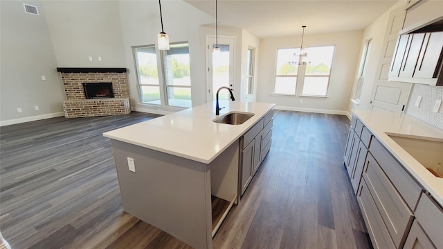 kitchen featuring a kitchen island with sink, hanging light fixtures, and gray cabinetry