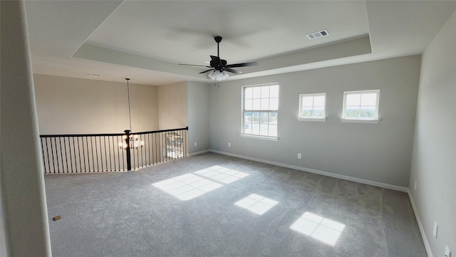 carpeted spare room featuring ceiling fan and a tray ceiling