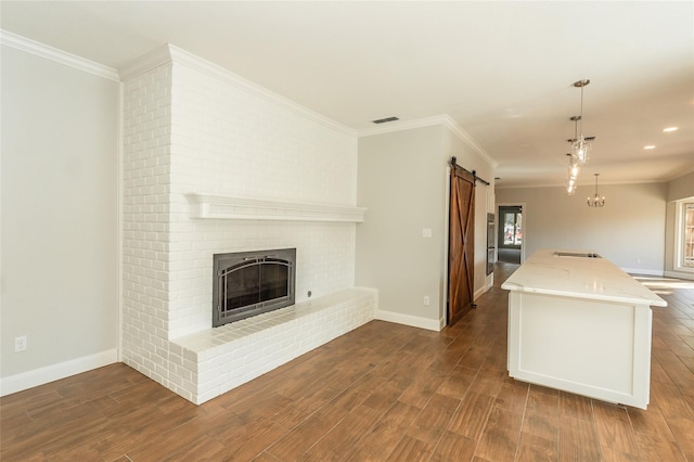 kitchen featuring pendant lighting, crown molding, light stone countertops, and a barn door