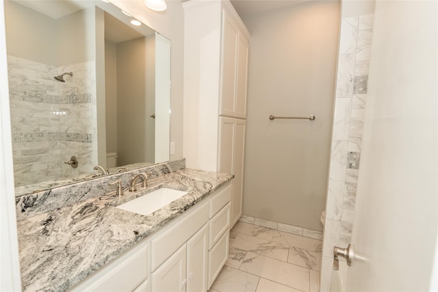 bathroom with tiled shower, vanity, and toilet