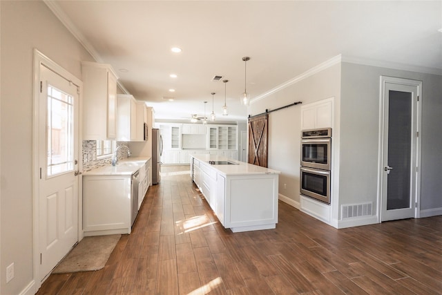 kitchen featuring pendant lighting, a barn door, white cabinets, and a center island