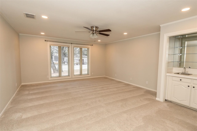 carpeted empty room with ceiling fan, ornamental molding, and wet bar