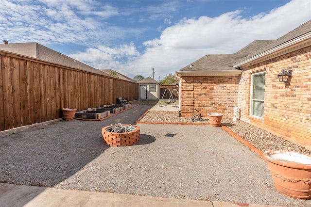 view of yard featuring a storage shed, a patio, and a fire pit