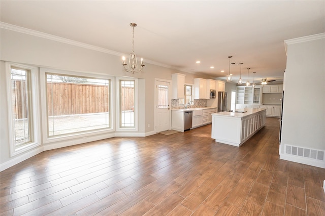 kitchen featuring a kitchen island, appliances with stainless steel finishes, sink, white cabinets, and hanging light fixtures