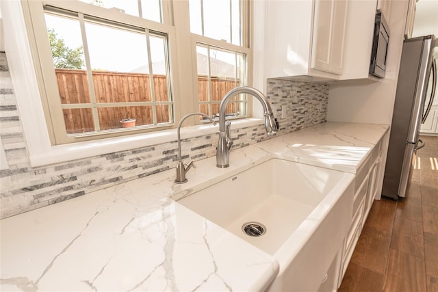 interior details with light stone counters, sink, stainless steel appliances, and white cabinets