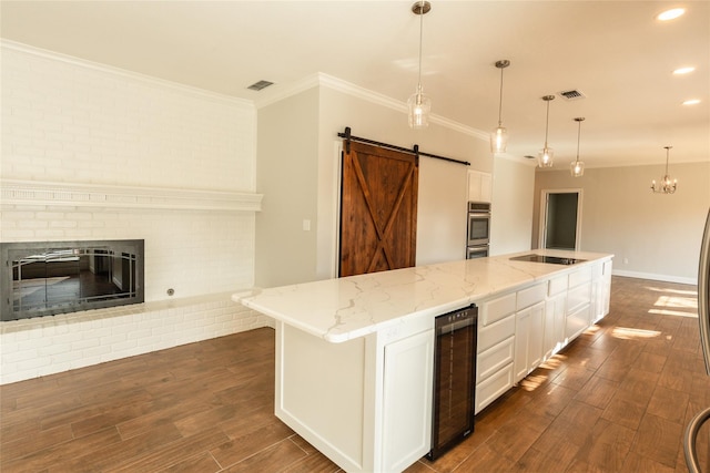 kitchen with pendant lighting, a kitchen island with sink, white cabinetry, wine cooler, and a barn door