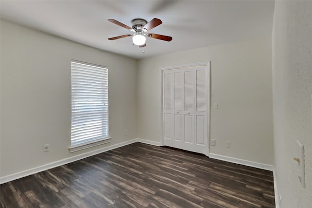 unfurnished bedroom featuring dark wood-type flooring, ceiling fan, and a closet