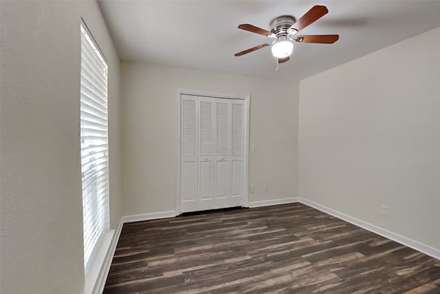 unfurnished bedroom featuring multiple windows, ceiling fan, dark hardwood / wood-style flooring, and a closet