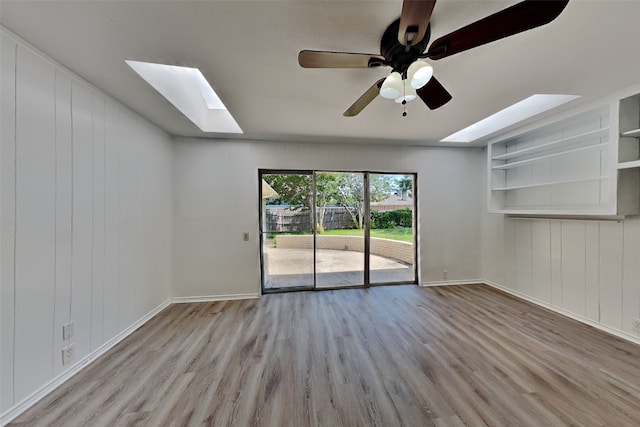 empty room with ceiling fan, a skylight, and light hardwood / wood-style flooring