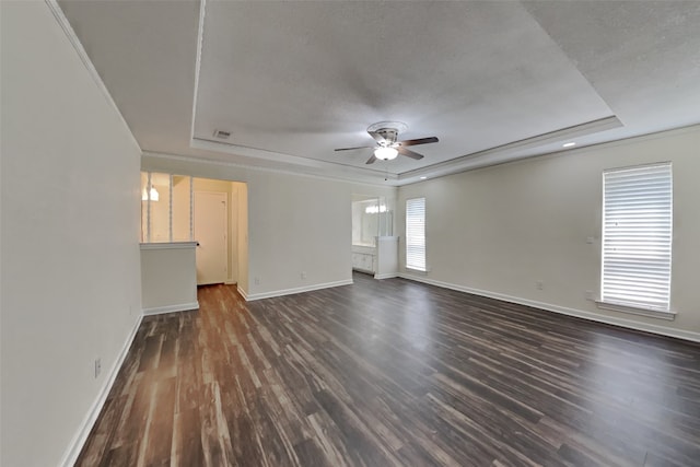 unfurnished living room with dark hardwood / wood-style floors, a textured ceiling, a raised ceiling, and a healthy amount of sunlight