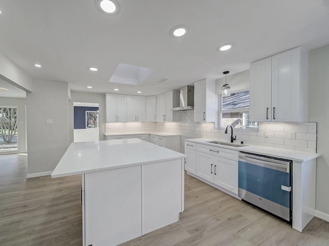 kitchen with white cabinetry, sink, wall chimney range hood, and dishwasher