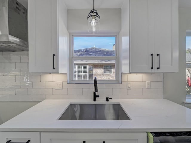 kitchen featuring light stone countertops, sink, wall chimney range hood, and decorative backsplash