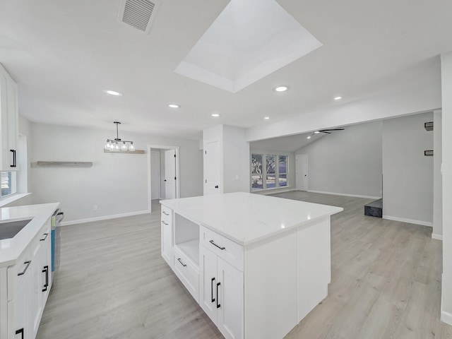 kitchen featuring ceiling fan with notable chandelier, white cabinetry, a center island, light hardwood / wood-style floors, and decorative light fixtures