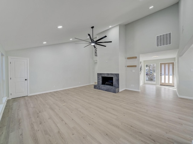 unfurnished living room with light hardwood / wood-style flooring, a fireplace, high vaulted ceiling, and ceiling fan