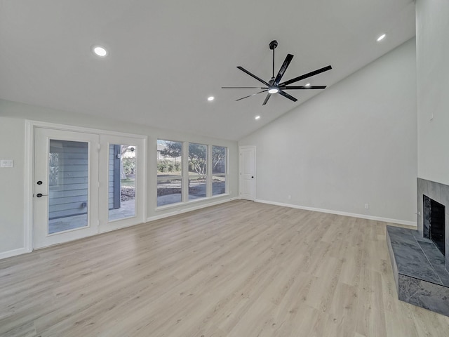 unfurnished living room featuring ceiling fan, high vaulted ceiling, a tiled fireplace, and light hardwood / wood-style floors