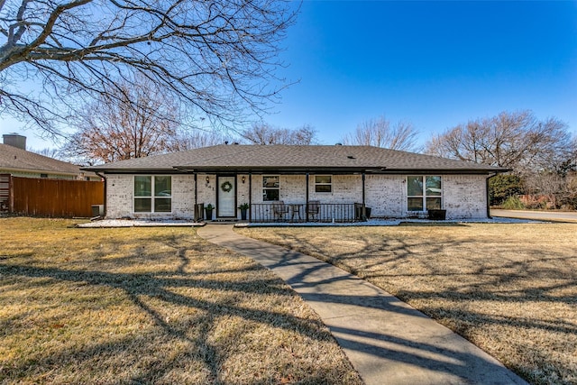 ranch-style house featuring covered porch and a front yard