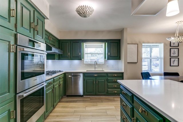 kitchen with sink, green cabinets, plenty of natural light, and appliances with stainless steel finishes