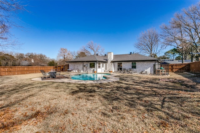 rear view of property with a fenced in pool, a yard, and a patio