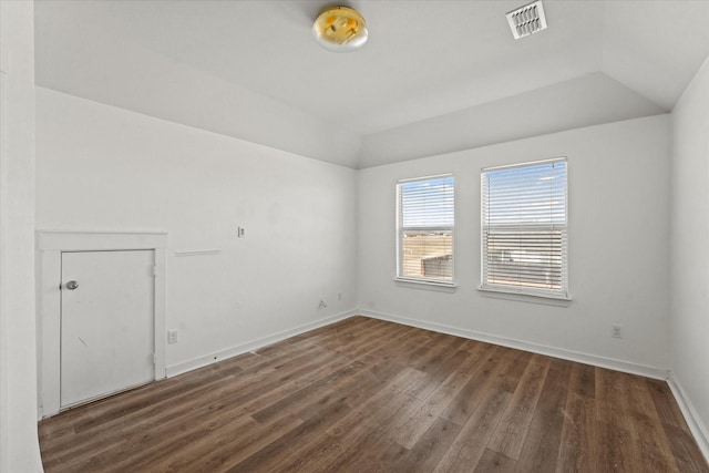 unfurnished room with lofted ceiling, dark hardwood / wood-style floors, and a raised ceiling