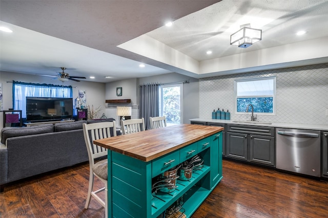 kitchen featuring butcher block countertops, sink, dishwasher, tasteful backsplash, and a kitchen island