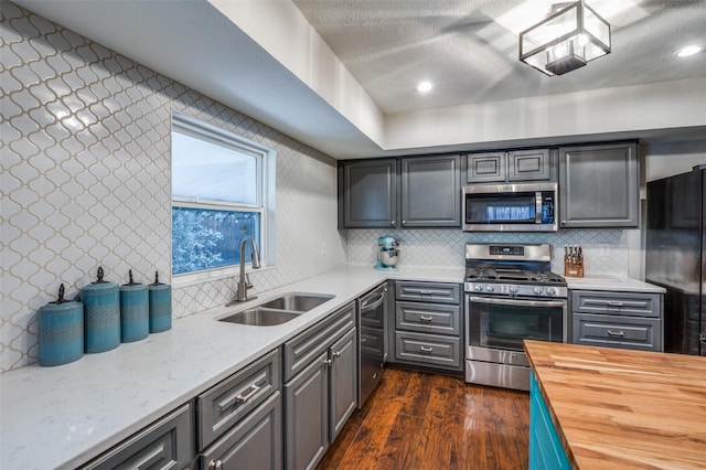 kitchen featuring wood counters, sink, dark hardwood / wood-style flooring, stainless steel appliances, and decorative backsplash