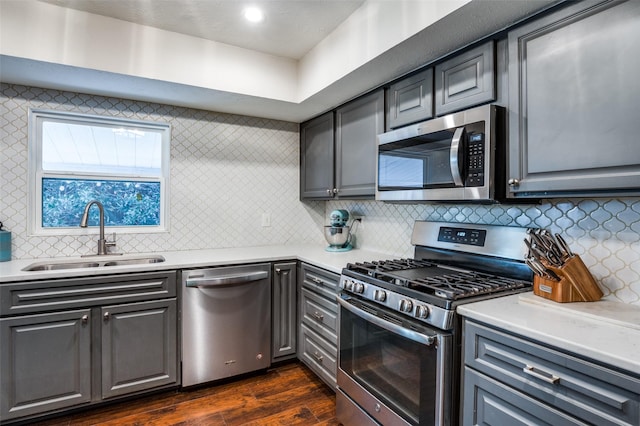 kitchen with appliances with stainless steel finishes, dark hardwood / wood-style flooring, sink, and backsplash