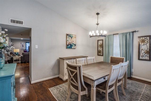 dining room featuring dark wood-type flooring, lofted ceiling, and an inviting chandelier